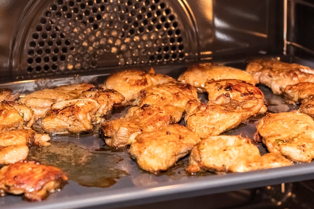 Rebanadas de filete de pollo frito en una parrilla metálica en el horno. Cocinar aves de corral