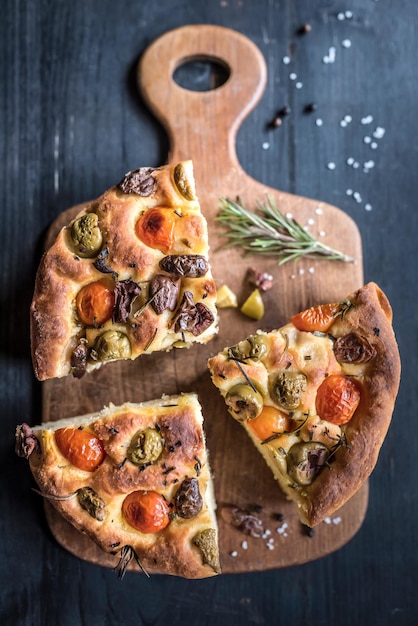 Rebanadas de Focaccia italiana casera con aceitunas y tomate en un enfoque selectivo