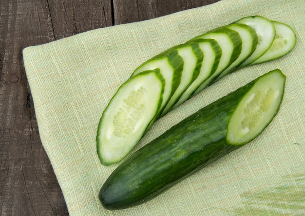 Rebanadas frescas del pepino en el fondo y el paño de madera oscuros