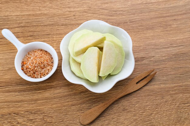 Rebanadas de guayaba fresca con una pizca de chile y sal servidas en un plato blanco