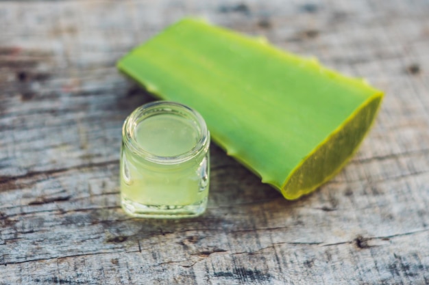 Rebanadas de una hoja de aloe vera y una botella con gel transparente con fines medicinales, tratamiento de la piel y cosméticos, cerrar