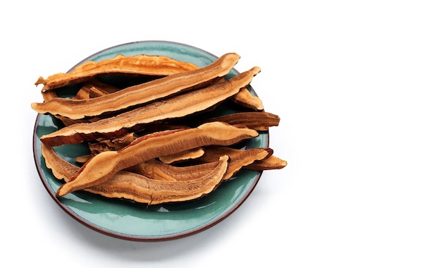 Rebanadas de hongos lingzhi secos sobre fondo blanco.