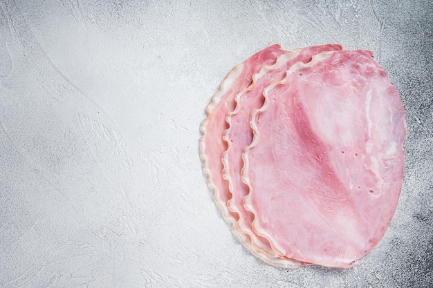 Rebanadas de jamón de cerdo fresco en la mesa de la cocina. Fondo blanco. Vista superior. Copie el espacio.