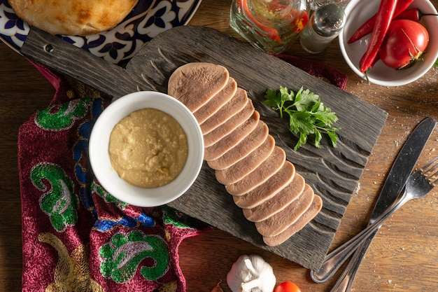 Rebanadas de lengua de ternera hervida con rábano picante y cilantro, en rodajas y servido en una tabla de cortar de madera