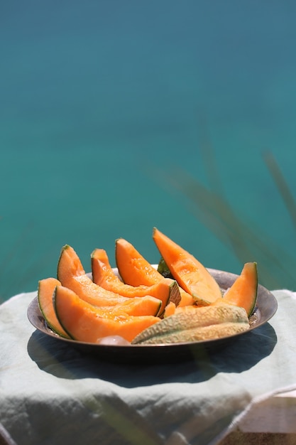 Rebanadas de melón naranja jugoso en un plato sobre un paño ligero
