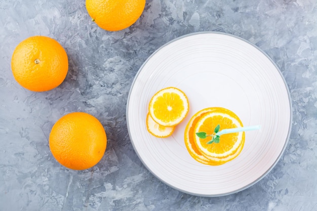 Foto rebanadas de naranja fresca en una pila de hojas de menta y una pajita para una bebida simulada de jugo de naranja