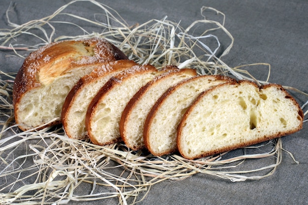 Rebanadas de pan blanco acostado en paja sobre un mantel de lino gris