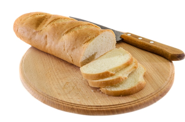 Rebanadas de pan blanco y un cuchillo sobre tablero de madera sobre fondo blanco.