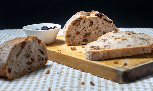 Rebanadas de pan casero con pasas, nueces y frutos secos sobre tabla de madera