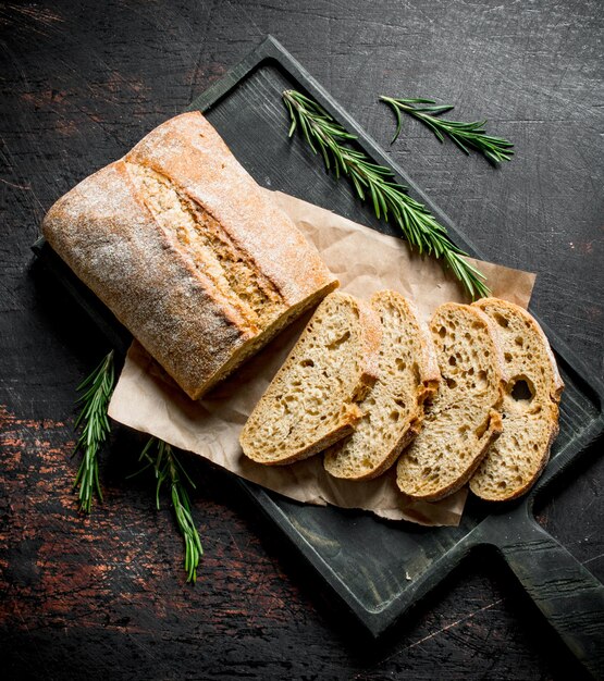 Rebanadas de pan ciabatta en una tabla para cortar con romero