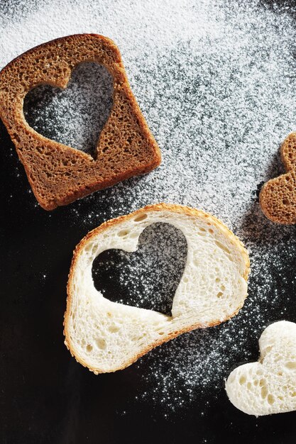 Rebanadas de pan con un corte en forma de corazón en la vista superior de fondo de metal negro