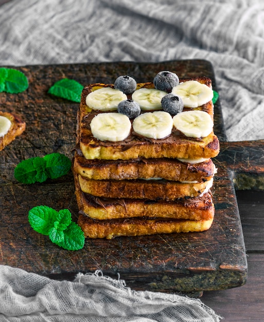 Rebanadas de pan frito cuadrado con chocolate y plátano.