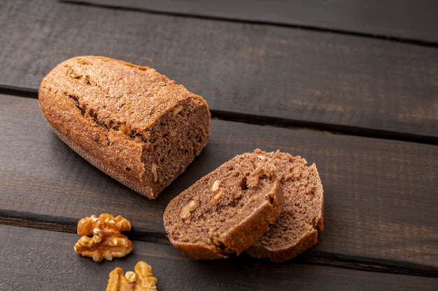 Rebanadas de pan de masa madre de nueces sobre fondo de madera oscura con espacio de copia