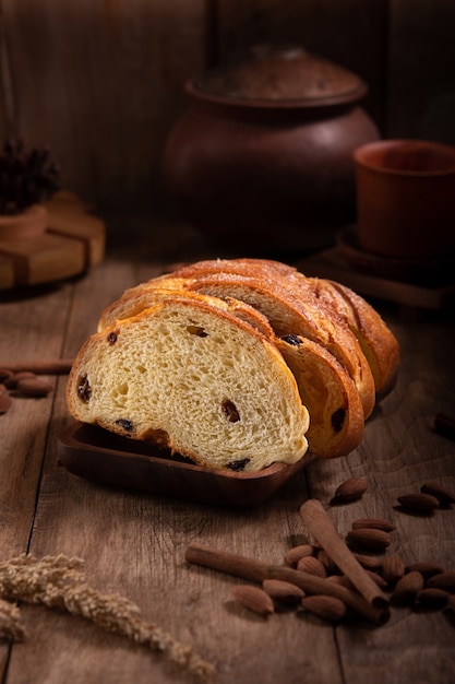 Rebanadas de pan de pasas servido en una mesa de madera con almendras y canela al lado