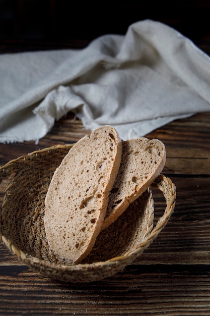 Rebanadas de pan rústico en un tazón de mimbre sobre una mesa de madera