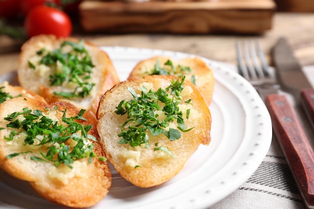 Rebanadas de pan sabroso con ajo y hierbas en la placa