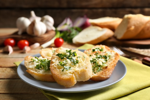 Rebanadas de pan sabroso con queso rallado, ajo y hierbas en la placa