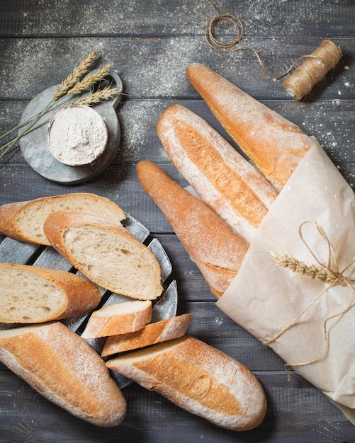 Rebanadas de pan sobre un fondo de madera Baguettes de la panadería Bodegón de pan Espigas de trigo y harina