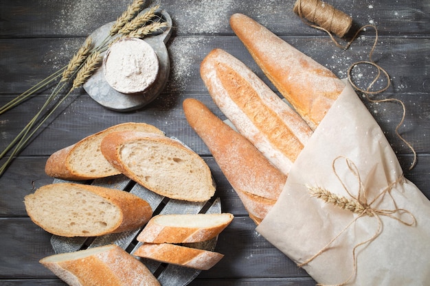 Rebanadas de pan sobre un fondo de madera Baguettes de la panadería Bodegón de pan Espigas de trigo y