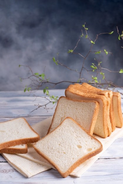 Rebanadas de pan sobre una mesa de madera blanca con una hermosa rama