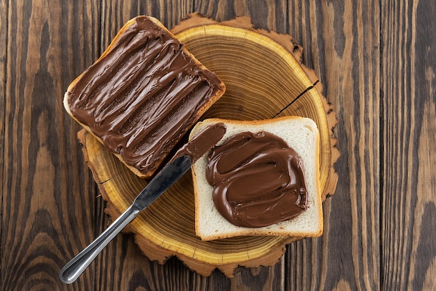 Rebanadas de pan tostado con chocolate y avellanas untadas con un cuchillo sobre una mesa Vista superior plana