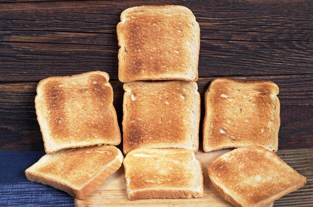 Rebanadas de pan tostado dispuestas como fondo en la mesa de madera oscura