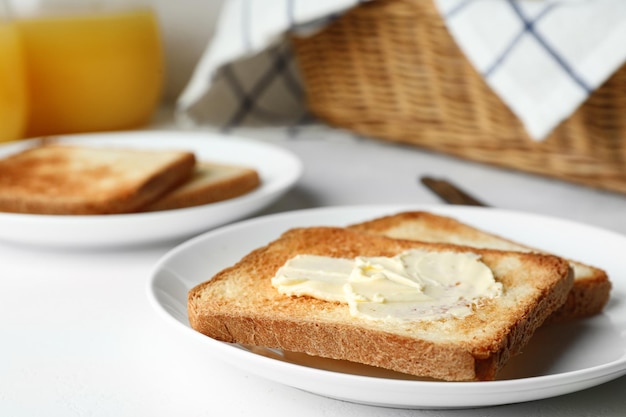 Rebanadas de pan tostado con mantequilla sobre mesa blanca