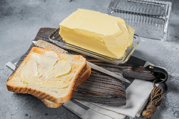 Rebanadas de pan tostado con mantequilla sobre tabla de madera Fondo gris Vista superior