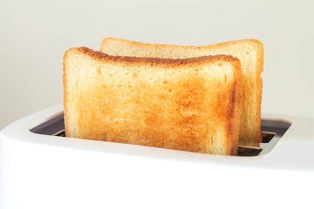 Rebanadas de pan tostado tostado en tostadora en la mesa de la cocina