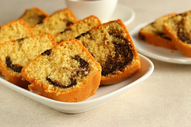 Rebanadas de pastel Bundt de mármol en plato blanco, servido con una taza de té