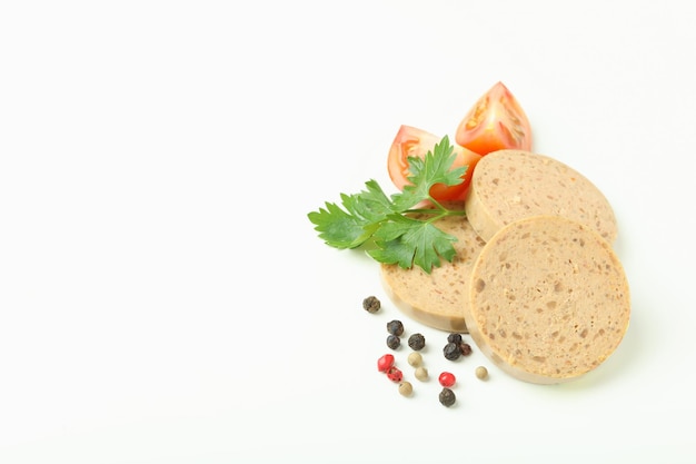 Rebanadas de paté de hígado tomate pimiento y perejil sobre fondo blanco.