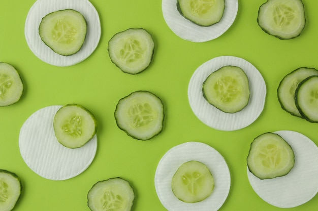 Rebanadas de pepino fresco y esponja de algodón sobre un fondo verde brillante. concepto de cosméticos de pepino. protección de la piel. extracto de pepino tónico