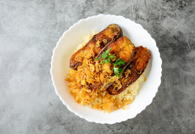 Rebanadas de pescado Pangasius con ajo frito, servido con arroz integral.