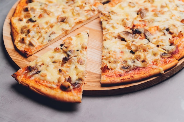 Foto rebanadas de pizza en bandeja de madera rústica y fondo oscuro.