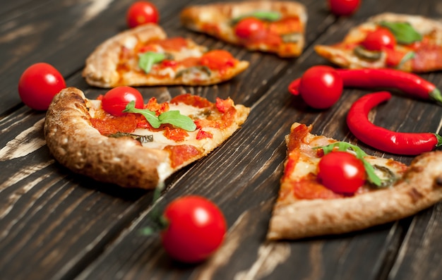 Rebanadas de pizza de pepperoni con ingredientes sobre fondo de madera