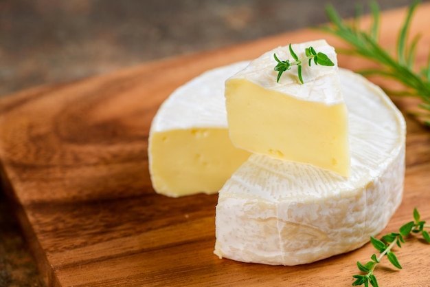 Rebanadas de queso Camembert con tomillo en placa de madera Camembert es un cremoso suave húmedo