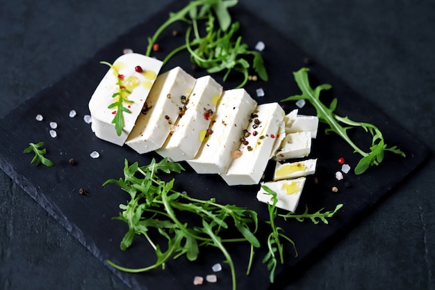 Rebanadas de queso feta con condimentos y aceite de oliva.