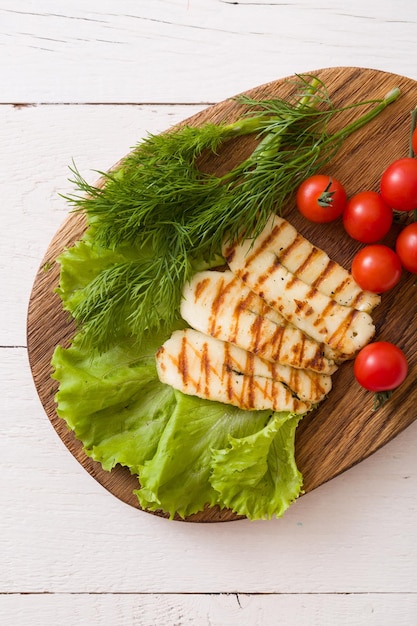 Rebanadas de queso halloumi casero a la plancha con ensalada verde, hierbas frescas y tomates orgánicos