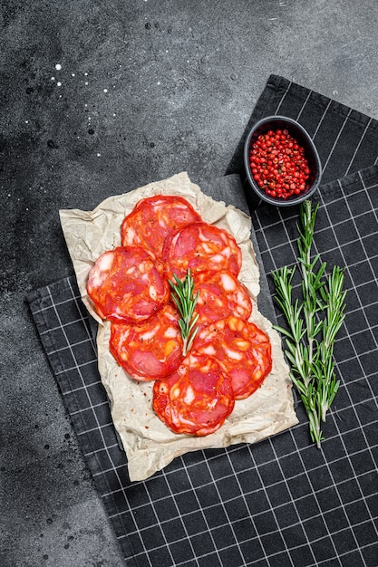 Foto rebanadas de salami de chorizo. chorizo tradicional español. superficie negra. vista superior