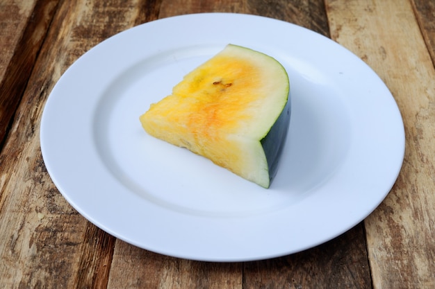 Rebanadas de sandía fresca en un plato blanco sobre fondo de madera