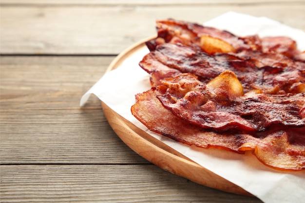 Rebanadas de tocino frito en la tabla de cortar