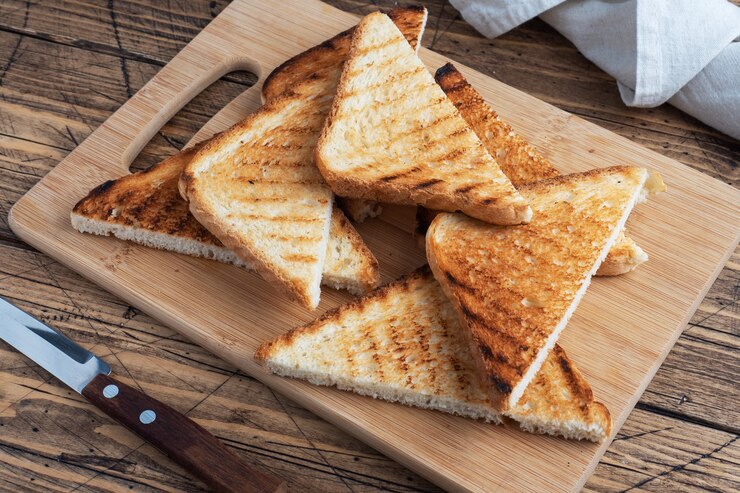 Rebanadas de tostadas de pan crujiente para sándwiches en una tabla de cortar, fondo rústico de madera. De cerca.