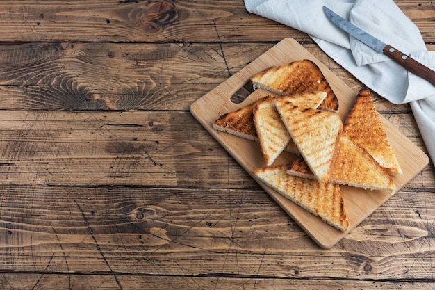 Rebanadas de tostadas de pan crujiente para sándwiches en una tabla de cortar, fondo rústico de madera. Copie el espacio.