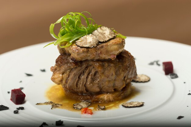 Rebanadas de trufas sobre un filete a la parrilla, carne de res y cerdo, con verduras y salsa