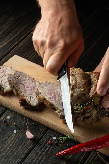 Foto rebanar jugoso filete de ternera con un cuchillo en manos de un chef cerrado el concepto de cocinar fondo oscuro para publicidad o receta