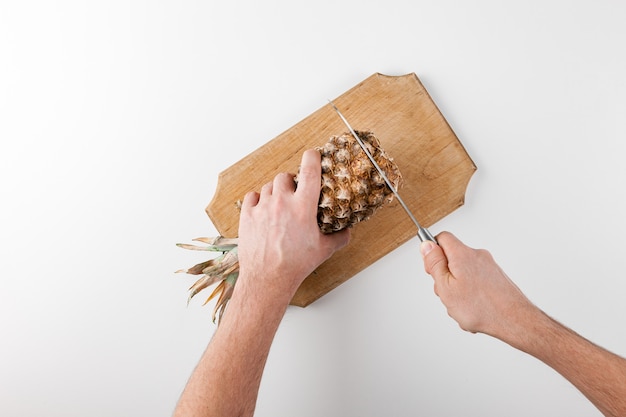 Rebanar la piña con un cuchillo sobre una tabla de cocina