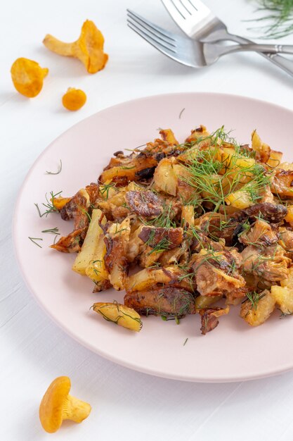 Rebozuelos fritos (Cantharellus cibarius) con patatas en un plato.