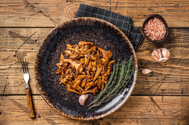 Rebozuelos fritos cocidos con cebollas y hierbas. Fondo de madera. Vista superior.