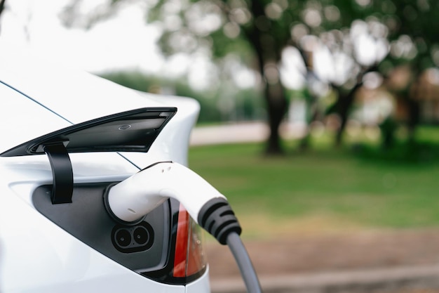 Foto recarga de bateria de veículo elétrico a partir de estação de carregamento de veículo eletrônico em parque urbano verde ao ar livre. proteção natural com viagens de carro elétrico ecológico exalt