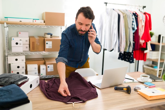 Recebi um novo pedido online de um cliente. Empresário ocupado multitarefa falando ao telefone e se preparando para enviar um pacote de sua loja de roupas